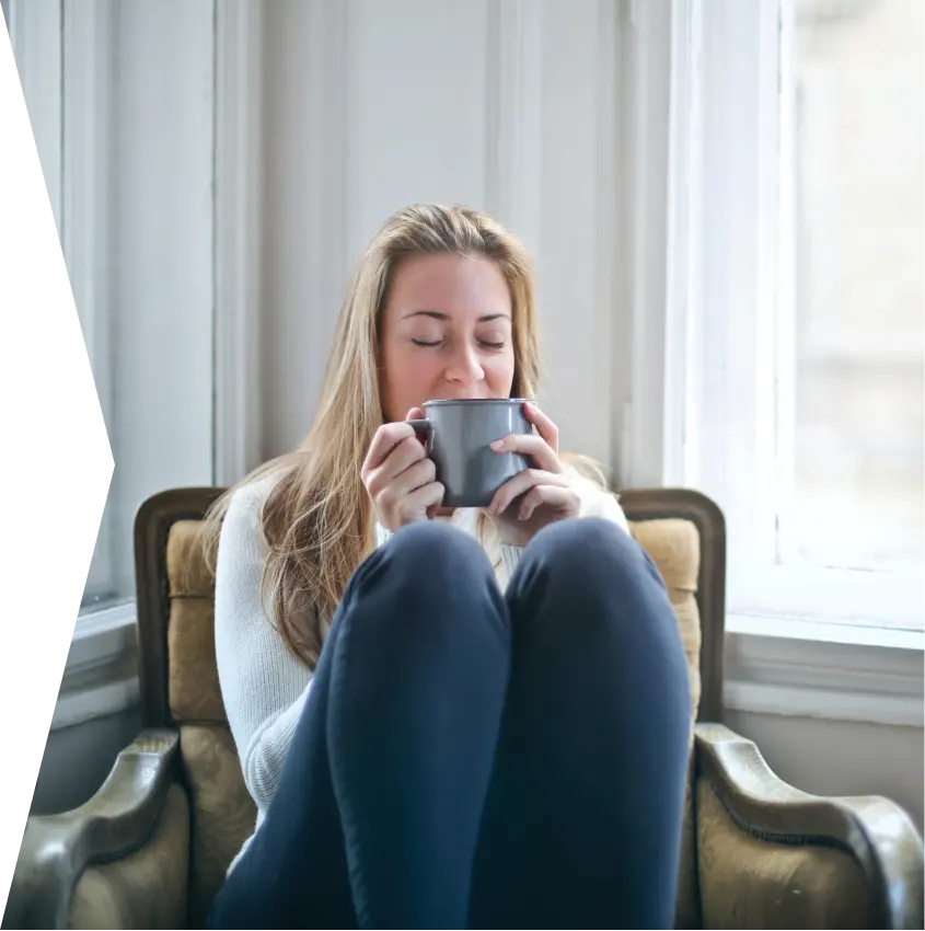 start-my-journey-cta-webp A picture of a woman sipping a cup of coffee while comfortably sitting on a chair.