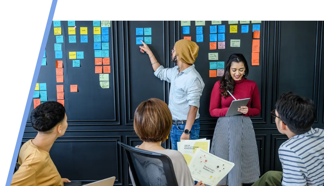 endless-options-webp An image of a group of people discussing using sticky notes with two standing in front of the three person sitting attentively.